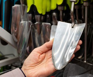 A hand lifting a trowel in a tool store