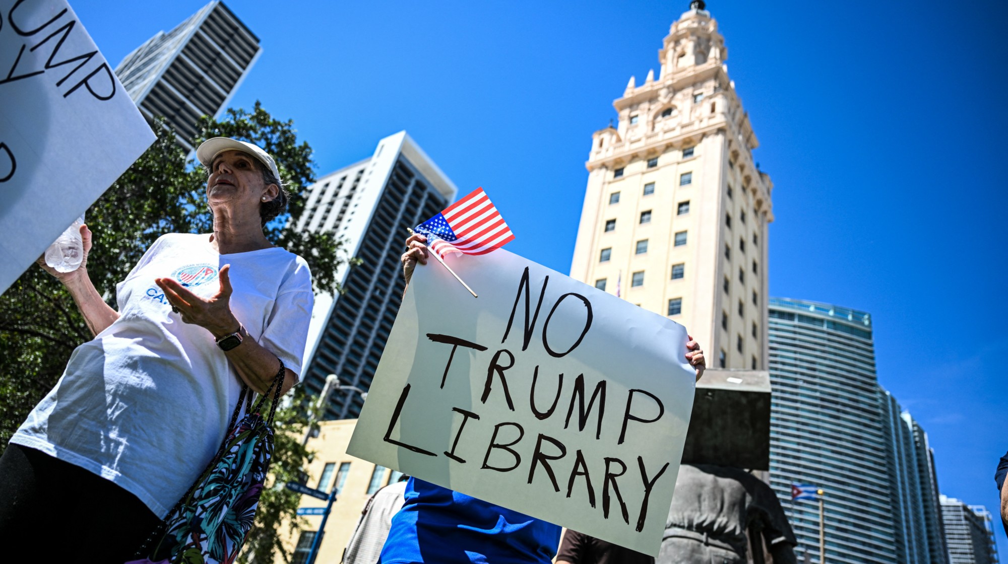 Protesters hold signs as they protest opposing plans to build a Trump library near Miami's Freedom Tower in Miami, Florida on September 29, 2025. 