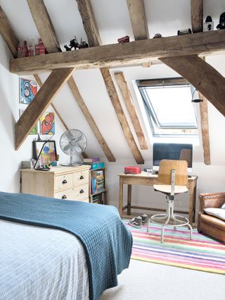 boys bedroom with spiderman artwork and striped rug and desk white walls with beams