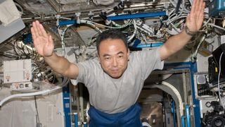 astronaut with hands outstretched floating in space station