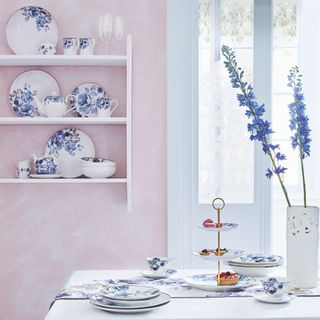 room with white flower vase pink wall and blue floral design crockery