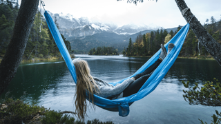 Woman relaxing in hammock beside a lake