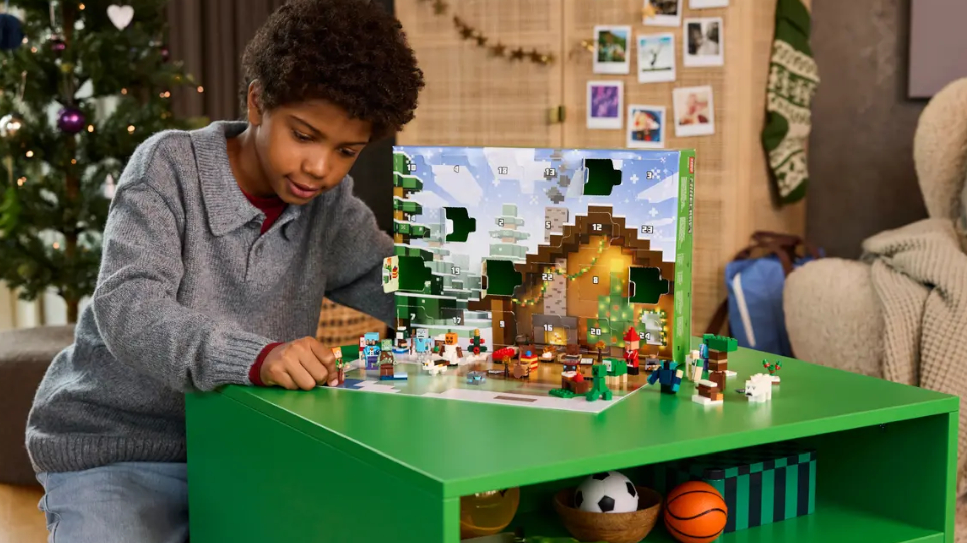A boy plays with the Lego Minecraft Advent Calendar on a green table, with a Christmas tree in the background