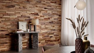A wall clad in narrow, horizontal wooden slats in varied warm tones. The layered wood creates texture and depth, with natural grain visible throughout. It feels warm and tactile, adding a calm, organic backdrop to the room.