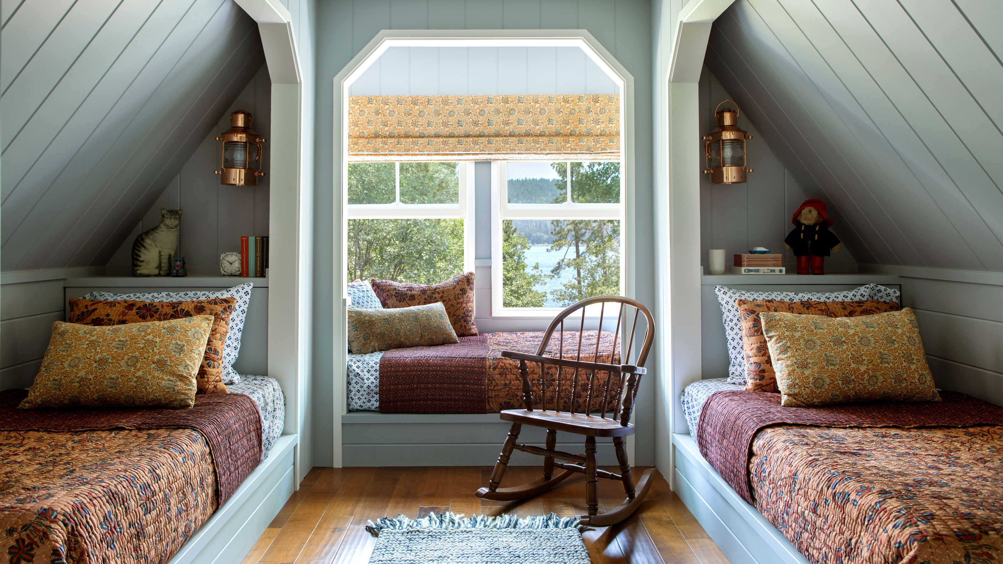 A loft bedroom with panelled walls and two twin beds with a patterned bedspread