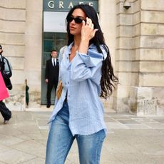 Dua Lipa wears a blue shirt, jeans and peep-toe mules as she walks down the street in Paris.