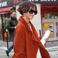 Halle Berry wears oversize sunglasses and a rust-colored jacket.