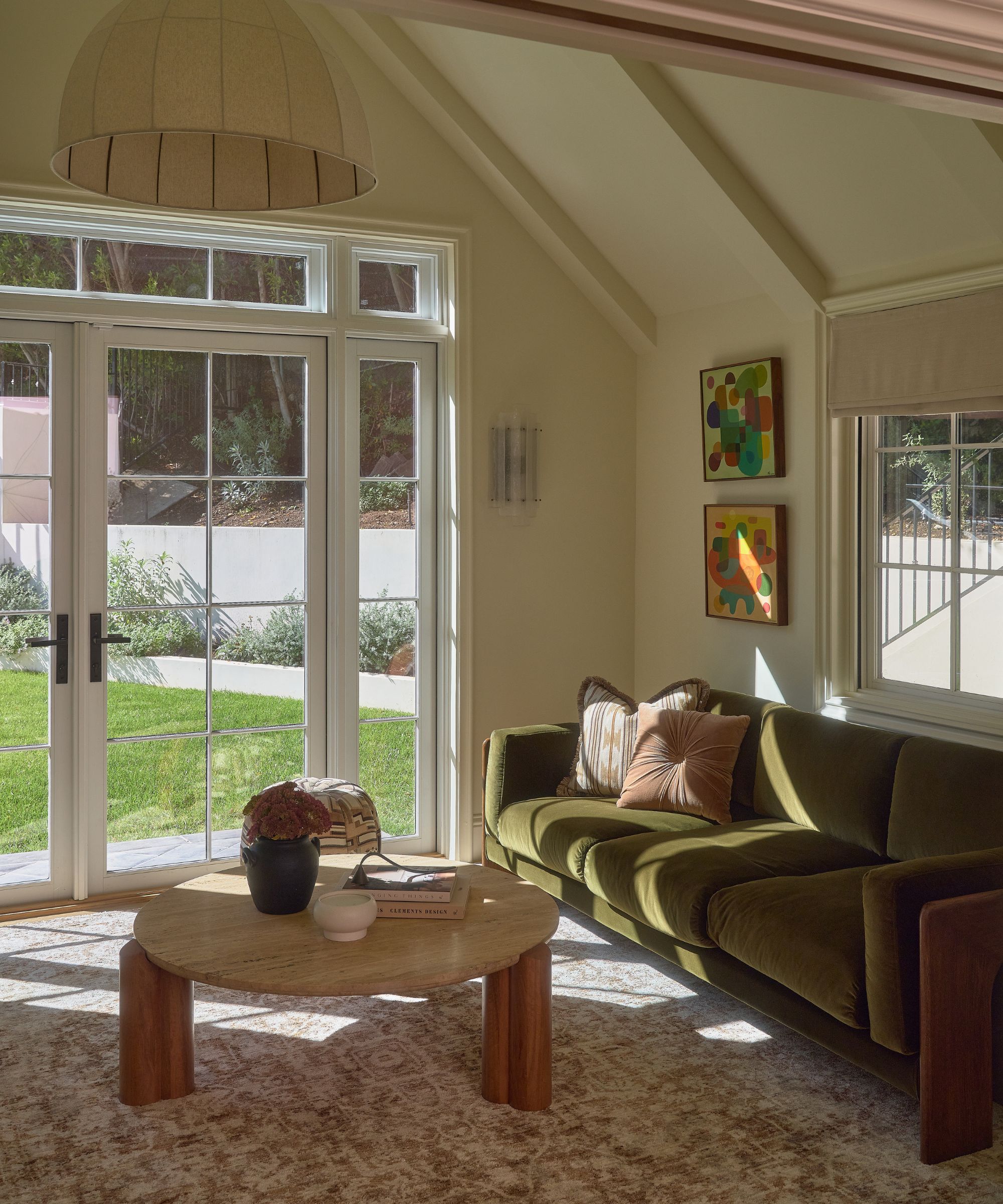 a primary bedroom suite with a lounge area with french doors, vintage style rug, green couch and coffee table