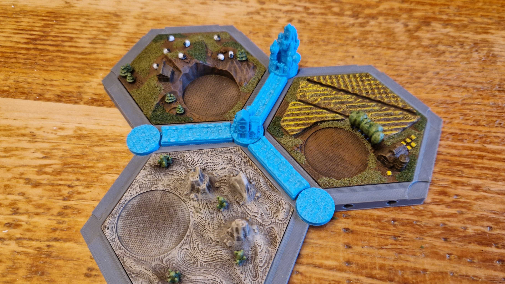 An assembled set of 3D Catan tiles featuring hand-painted fields, pastures, and desert terrain