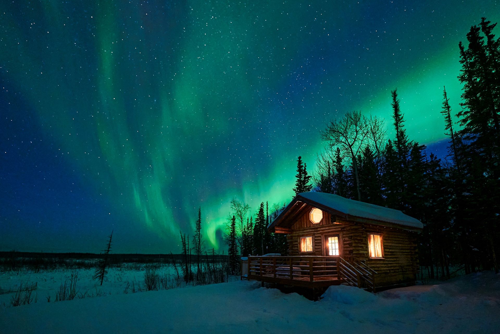 A peaceful scene of a cabin in a snowy Alaskan landscape with the northern lights overhead.