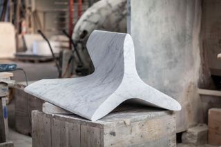 A smooth white marble triangular shape which is used as the tables legs.