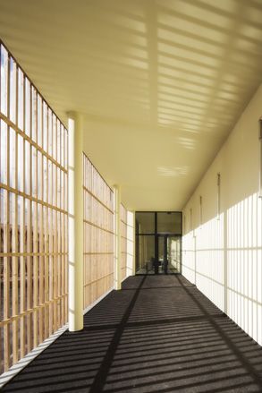 Walk way of building's corridor with sun shining through the bars