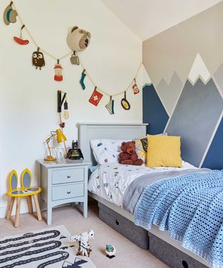 childrens room with wall painted mluntain scene, bunting and animal head wall art