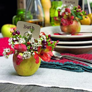 A table setting with seating cards, apple and flower decorations