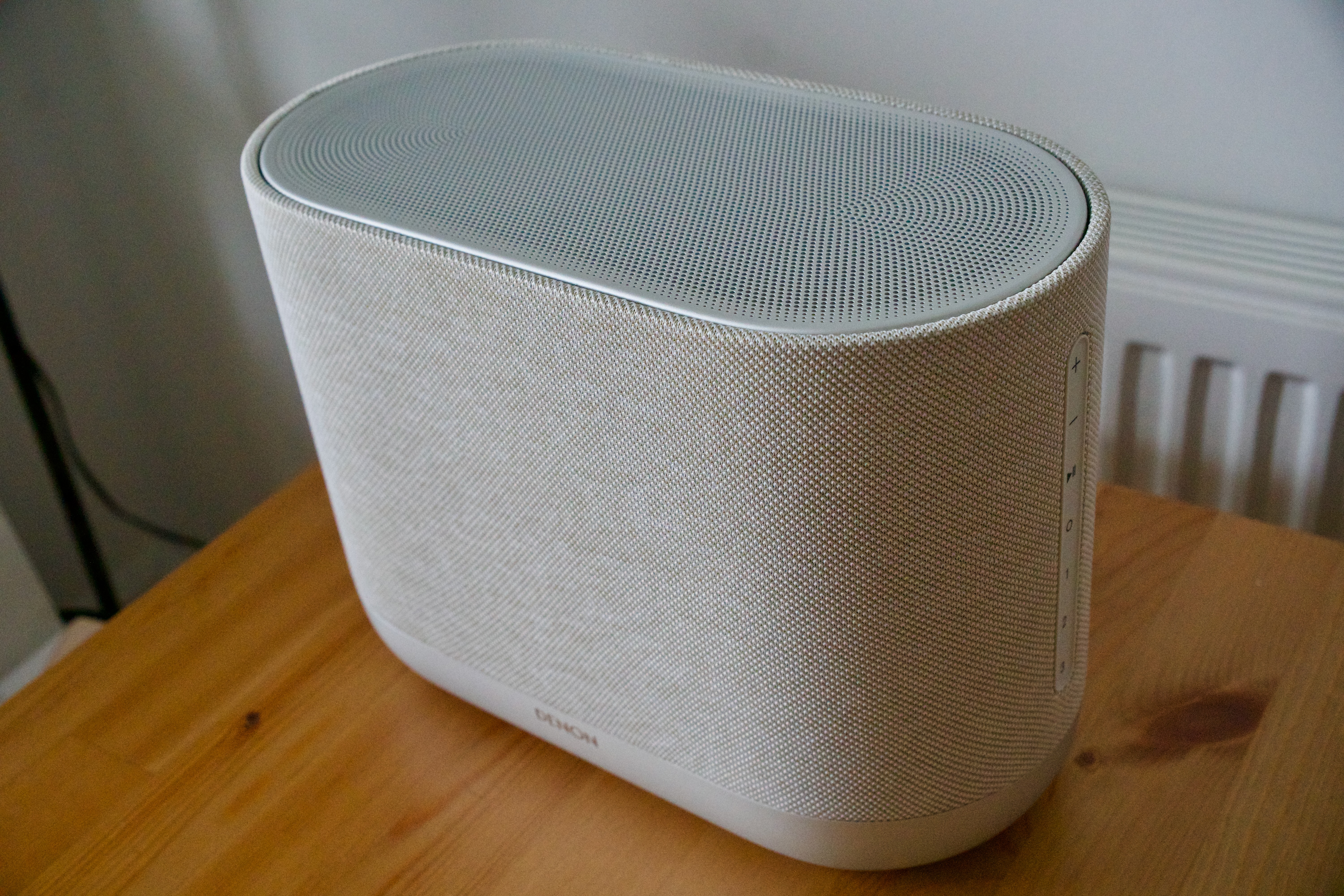 Denon Home 400 home speaker unit, on a wooden surface.