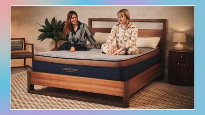 Two mattress testers sit on the Brooklyn Bedding CopperFlex Hybrid mattress on a bed frame in a warmly lit room.