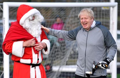 CHEADLE HULME, UNITED KINGDOM - DECEMBER 07: British Prime Minister Boris Johnson greets a man dressed as Father Christmas during the warm up before a girls' soccer match between Hazel Grove 