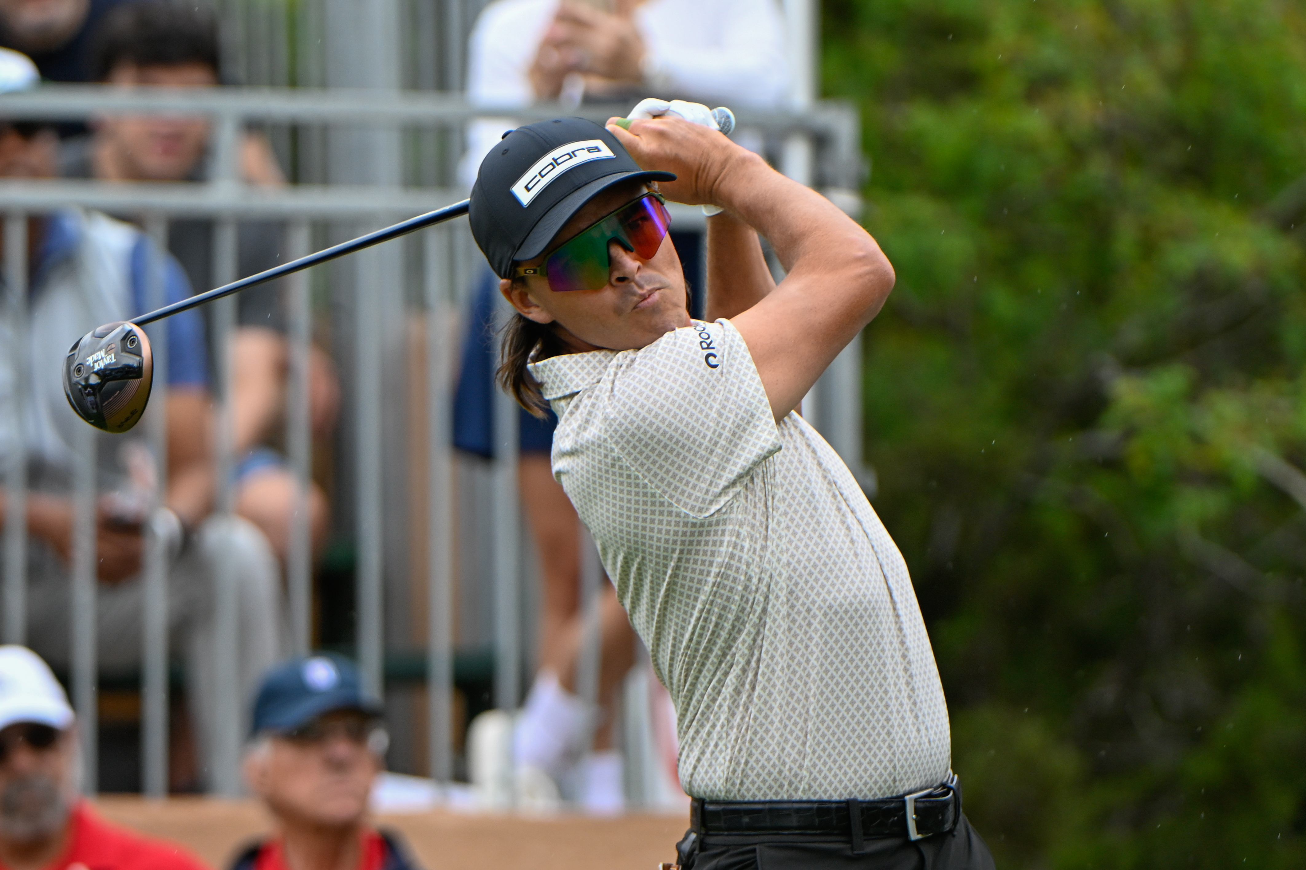Rickie Fowler hits a tee shot and watches it