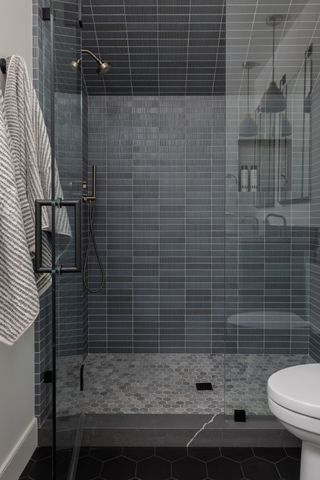 A shower with blue tiles walls and mosaic tiles floor