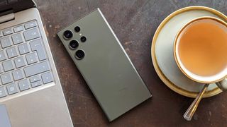 Samsung Galaxy S23 Ultra met scherm op tafel tussen laptop en kop thee in