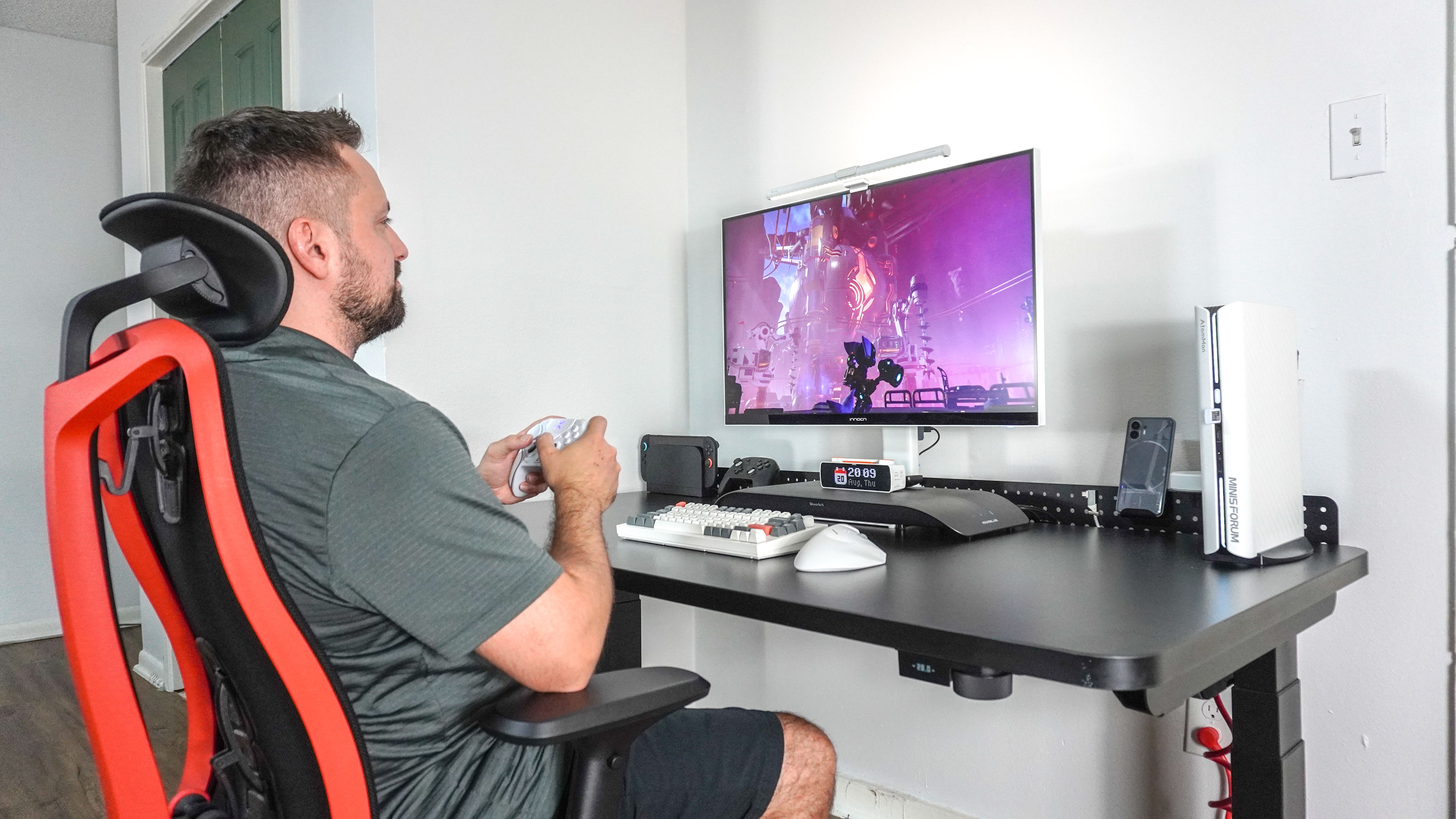 A person sitting in the Herman Miller Vantum gaming chair playing games at a desk setup built on top of the Herman Miller Coyl Gaming Desk