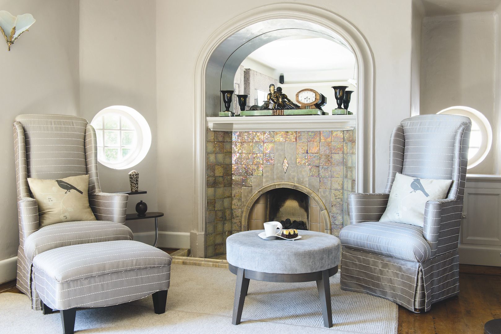 A clean grey living room with tall back chairs and a fireplace