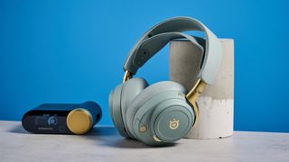 The SteelSeries Arctis Nova Elite with its USB hub on a stone surface with a blue background