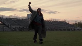 Judd Nelson raising his fist in the air as he walks across a sports field at the end of The Breakfast Club