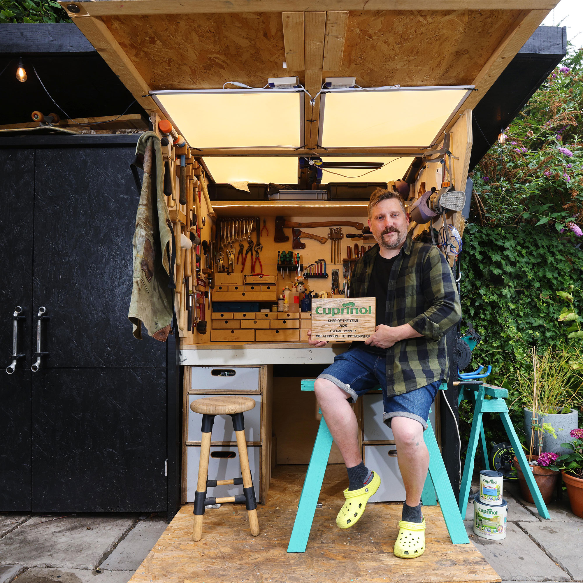 Cuprinol shed of the year in black with spanner handles and wooden workshop desk hidden inside