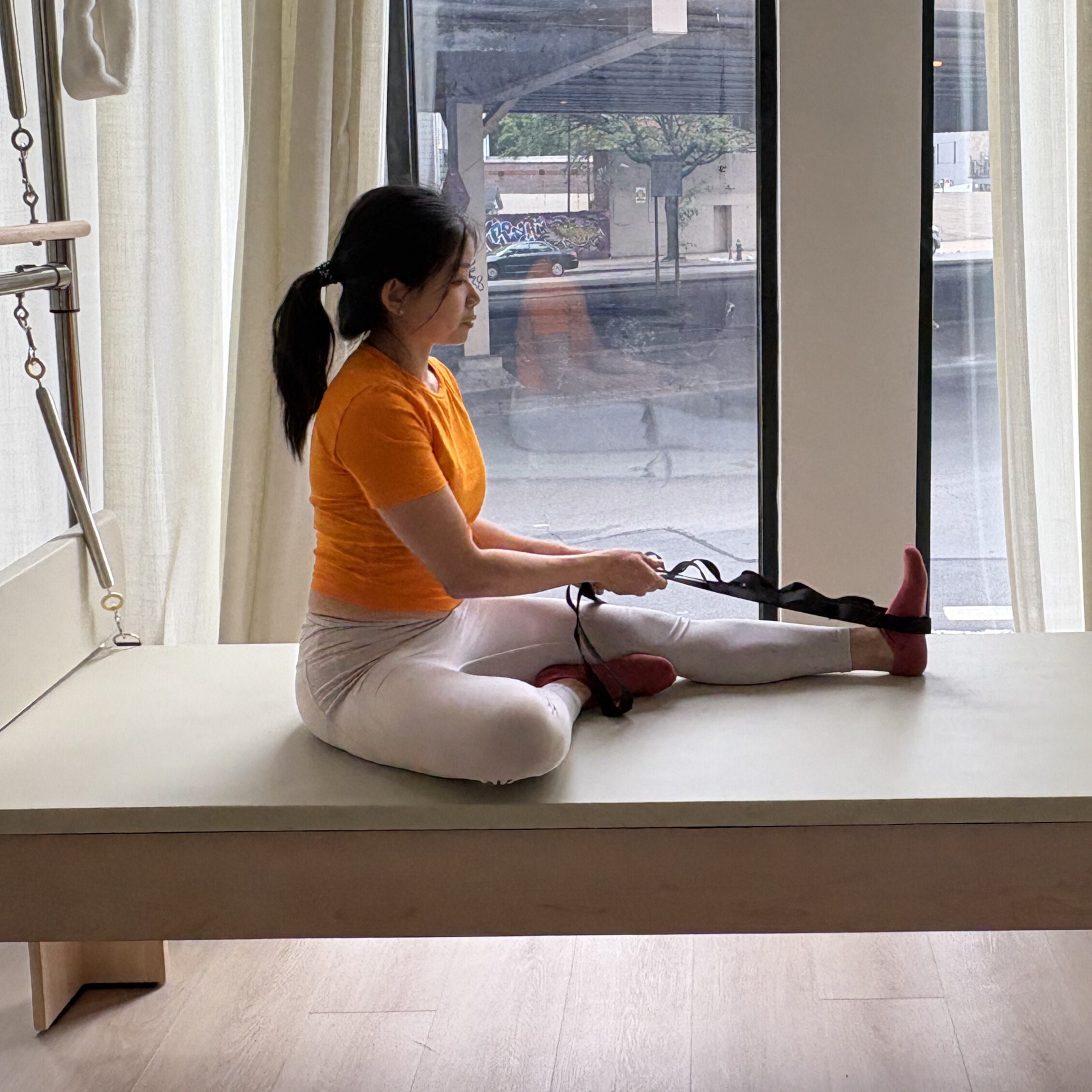 Woman demonstrates exercise on reformer bed