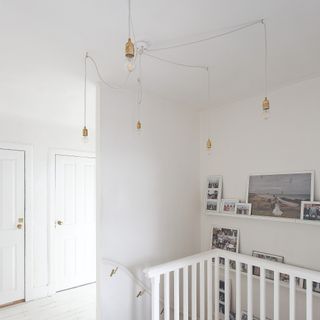 A white hallway with a staircase and a spider light fixture with Edison-style light bulbs