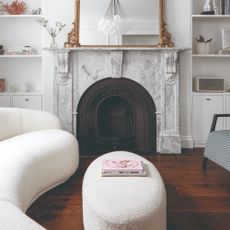 A curved boucle sofa in a living room with a fireplace