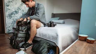Man sitting on his bed packing his backpack