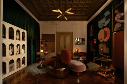 an entertainment room in the artemest apartment at milan design week 2025, with a dual facing sofa, and art present in arched shelving