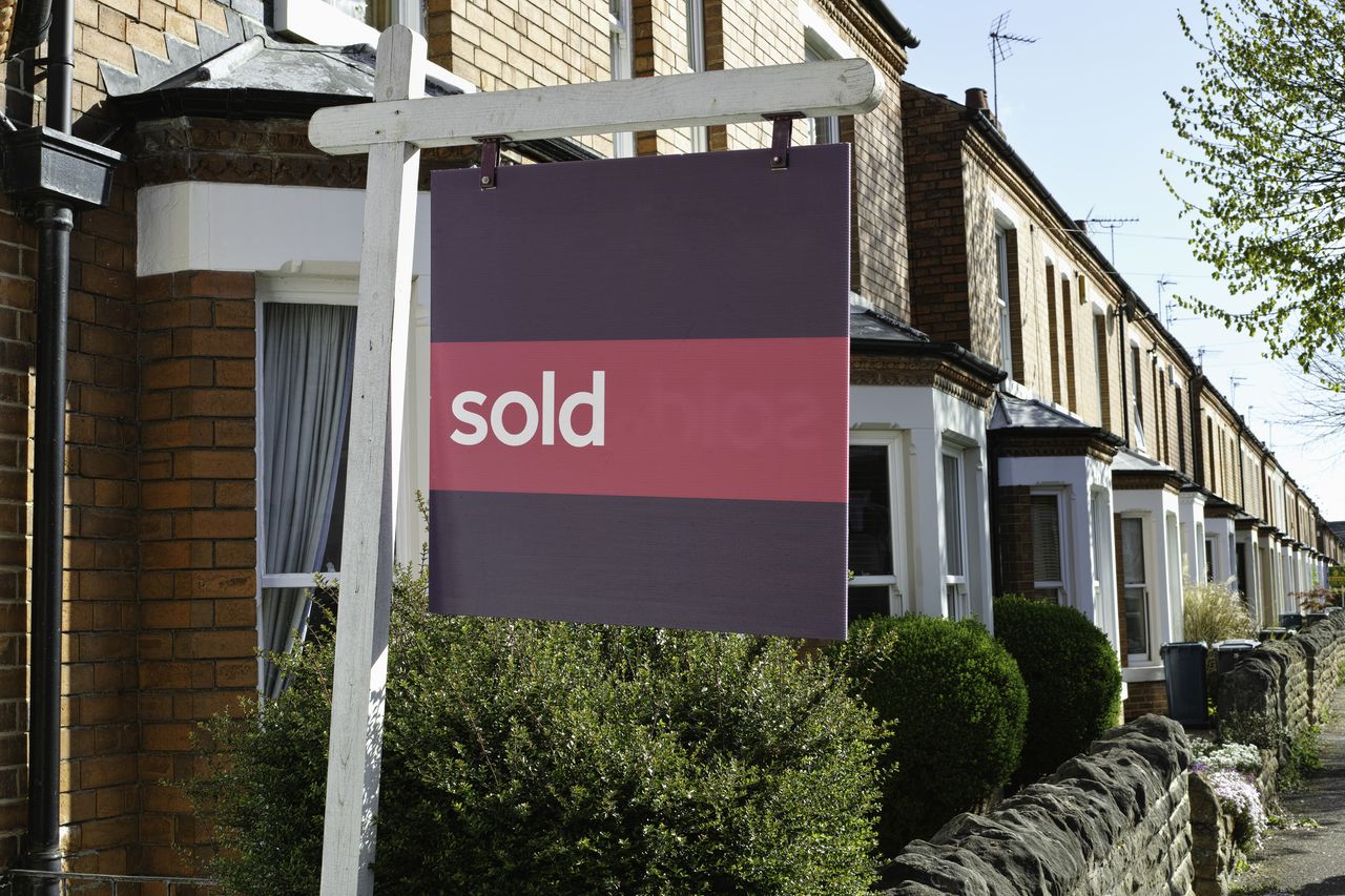 UK sold house prices symbolised by a &#039;sold&#039; sign outside a terraced house