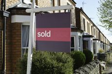 UK sold house prices symbolised by a 'sold' sign outside a terraced house