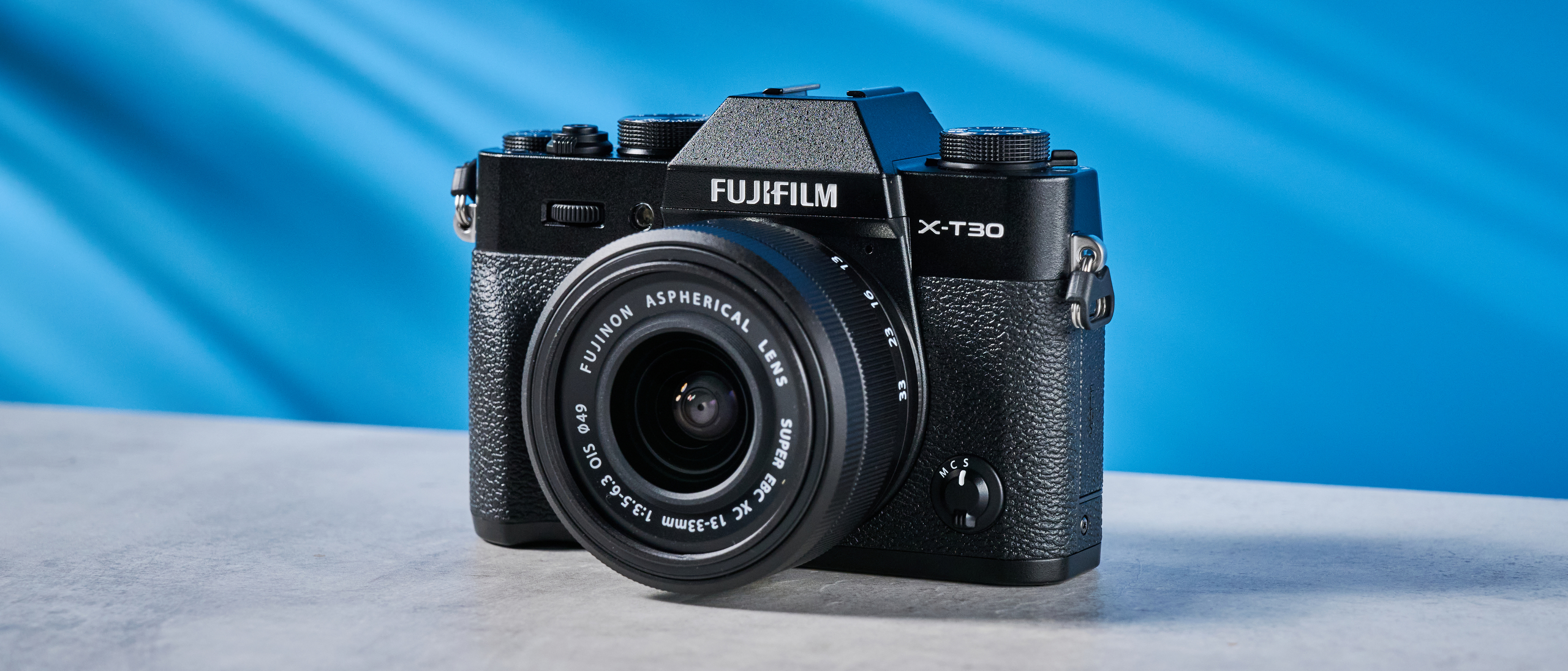 The Fujifilm X-T30 III on a stone surface with a blue background