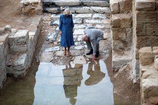 Prince Charles, Prince of Wales, touches the water next to Camilla, Duchess of Cornwall, during a visit to the baptism site