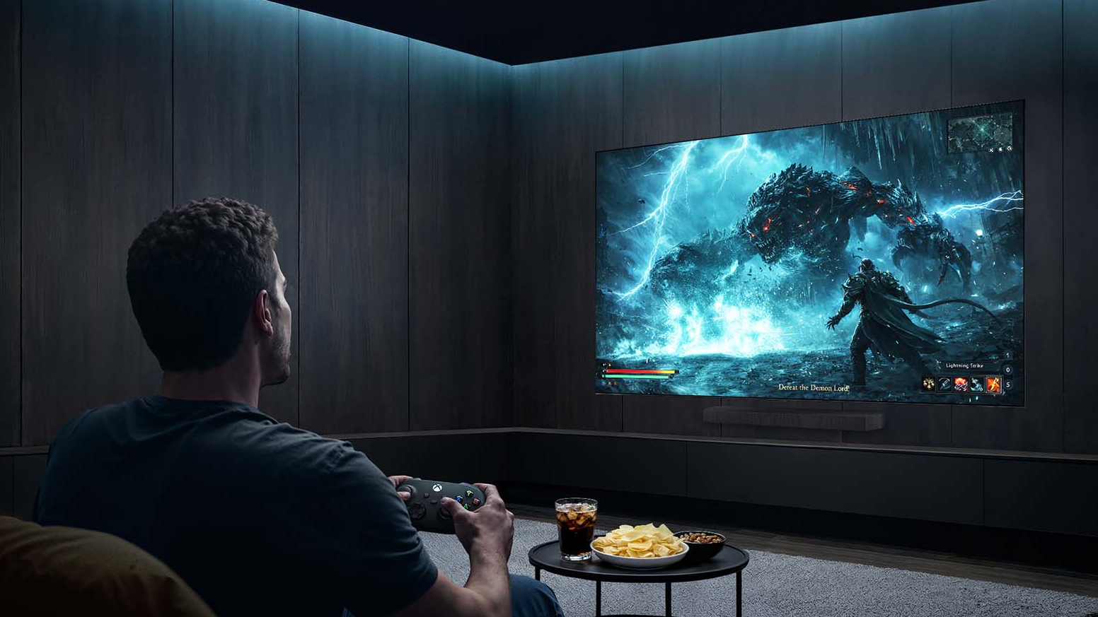 A person holding an Xbox controller in a dark room while a wall-mounted Samsung S90H displays a fantasy-like gaming sequence