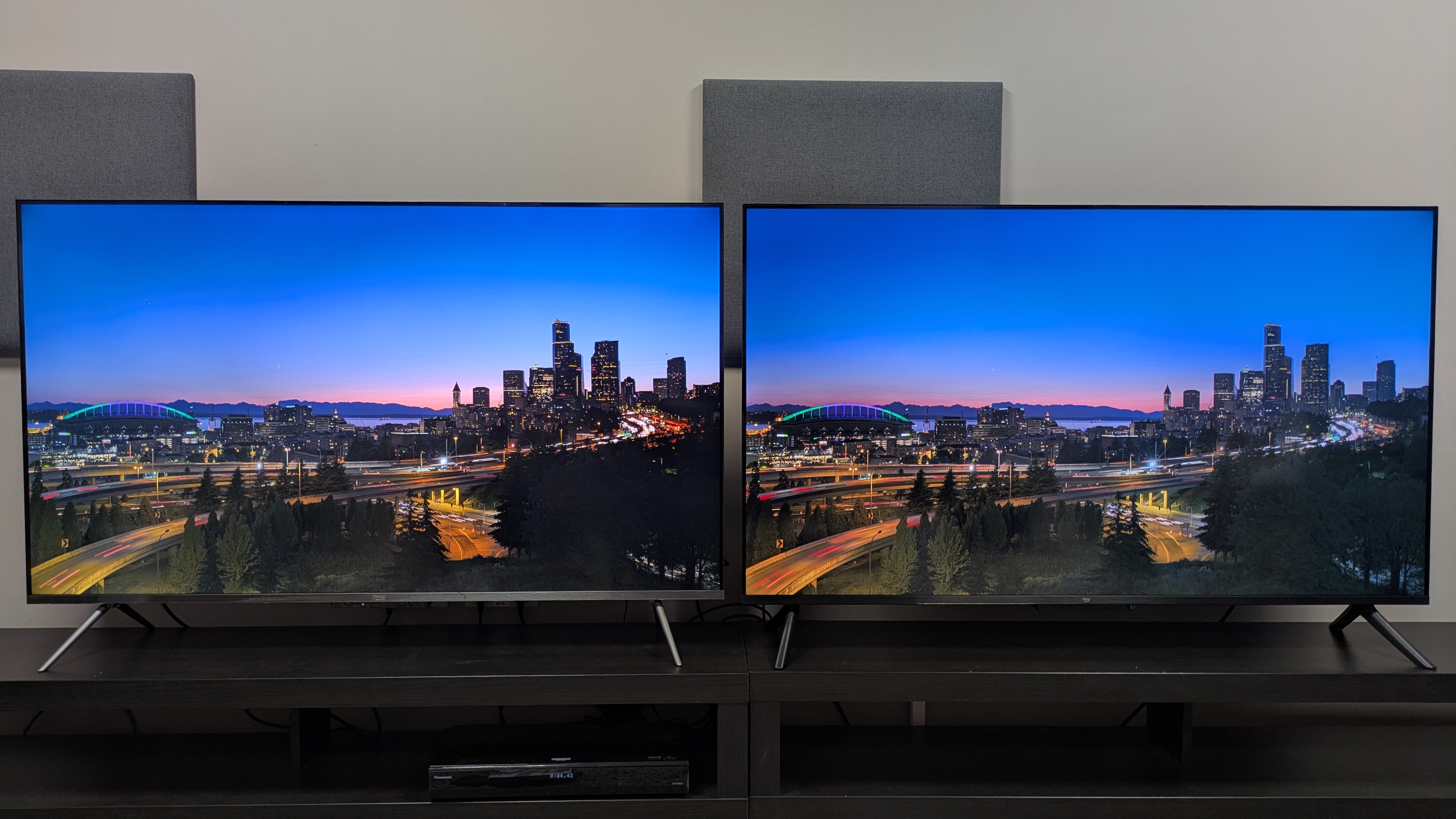 Amazon Ember QLED (left) and Amazon Ember 4-series (right) showing a skyline at dusk on screen. The Ember QLED shows stronger contrast with brighter highlights