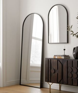 Two arched black mirrors next to a brown console table