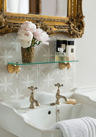 bathroom sink with antique mirror and antique glass of flowers