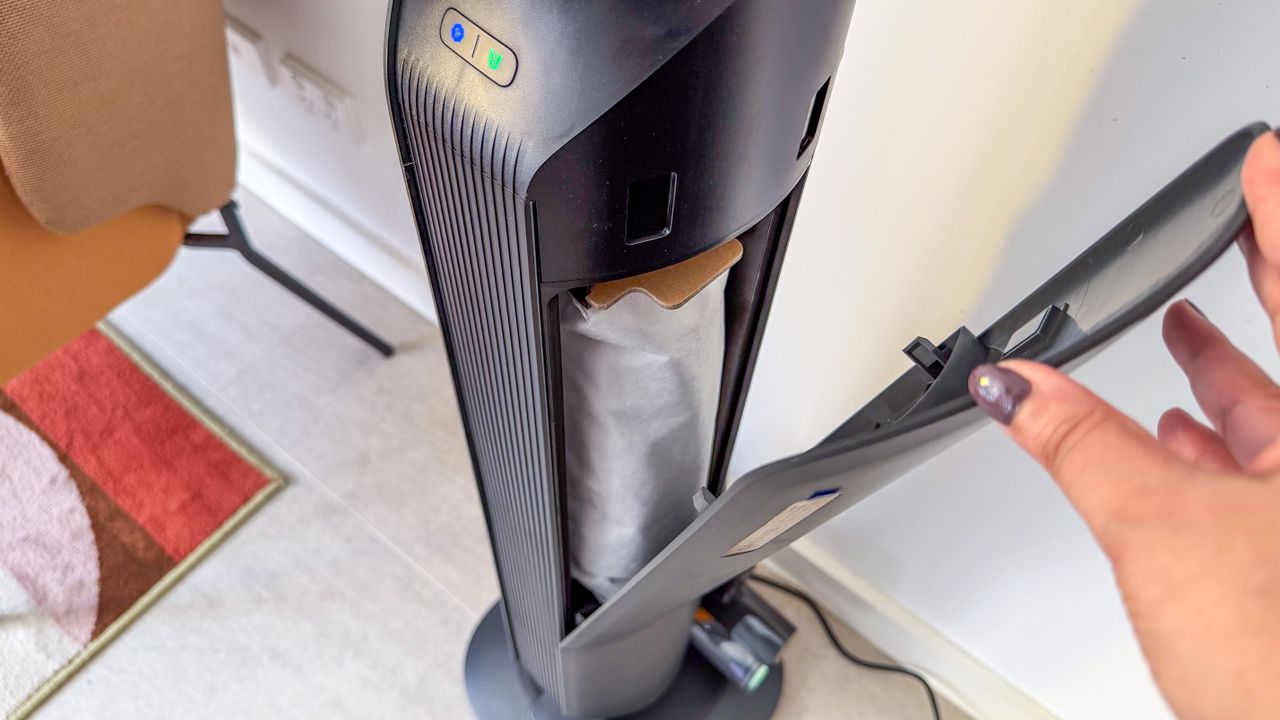 A person holding open the side panel on the Dreame Z50 Station dock to reveal the dust bag