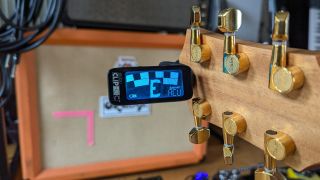 A Peterson Stroboclip HDC clip-on tuner attached to a Taylor acoustic guitar headstock