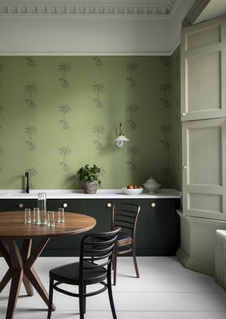green and white kitchen with green wallpaper dark green units and pale green woodwork and shutter