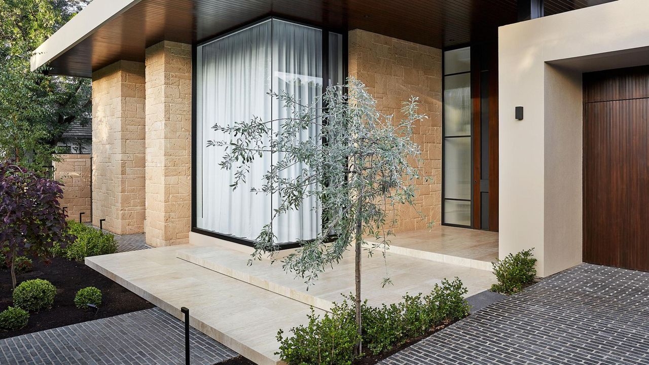 An outdoor space with limestone walls. Green foliage is scattered around the front of the home