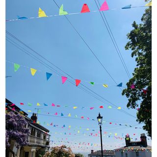 rainbow bunting in a residential street, with the sun shining in a blue sky