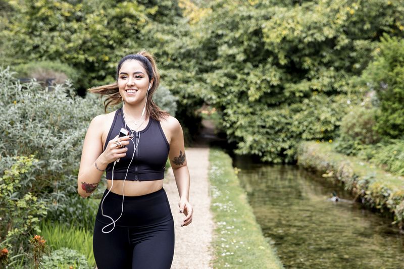 A woman running through a park next to small stream