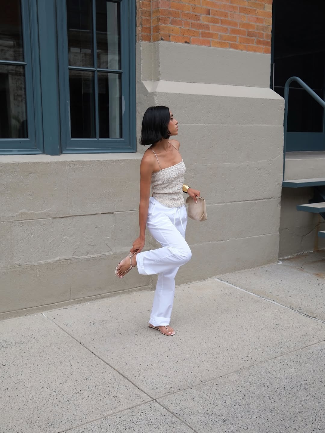 @shayinjune wearing a beige tank top with white poplin pants and stretch thong flat sandals.