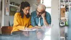 A couple look at financial paperwork at their kitchen table. 